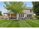 Well-manicured backyard with a covered patio area, a fire pit, and expansive green space at 11844 Pine Meadow Cir, Fishers, IN 46037