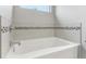 Close-up view of white bathtub with mosaic tile accents and chrome faucet and shower fixtures at 11844 Pine Meadow Cir, Fishers, IN 46037