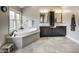 Bathroom featuring a soaking tub and double vanities with marble countertops and tile floor at 12437 Meeting House Rd, Carmel, IN 46032