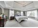Primary bedroom featuring tray ceilings, neutral decor, and large windows allowing ample natural light at 12437 Meeting House Rd, Carmel, IN 46032