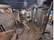 Unfinished basement with exposed ductwork, concrete walls, and various storage items at 1433 N Denny St, Indianapolis, IN 46201
