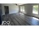 Spacious living room featuring wood-look floors, neutral gray walls, and natural light from multiple windows at 1527 Main St, Beech Grove, IN 46107