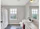 Bright bathroom featuring gray tones, a shower with a white curtain, and a window at 158 Handley St, Indianapolis, IN 46222