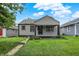 Charming single-story home featuring a well-maintained lawn and inviting front porch under a blue cloudy sky at 1722 Dawson St, Indianapolis, IN 46203