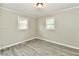 Bedroom featuring light gray walls, plank flooring, a ceiling light, and two windows at 1730 N Graham Ave, Indianapolis, IN 46218