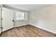 Bright bedroom with wood-look flooring, a window with blinds, neutral paint, and a white entry door at 1730 N Graham Ave, Indianapolis, IN 46218