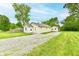 Charming single-story home with a gravel driveway and a detached garage, surrounded by lush greenery and mature trees at 1730 N Graham Ave, Indianapolis, IN 46218