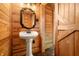 Rustic bathroom featuring a pedestal sink, decorative mirror, and natural wood paneling at 242 W Warford Dr, , IN 46164