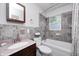 Bathroom featuring a single sink vanity with a decorative mirror, a window, and a tub with tiled walls at 318 S Routiers Ave, Indianapolis, IN 46219