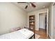 Cozy bedroom featuring wood flooring, a ceiling fan, and a bookshelf with an open doorway to the bathroom at 318 S Routiers Ave, Indianapolis, IN 46219
