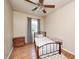 Small bedroom featuring wood flooring, a ceiling fan, neutral walls, and a small bed with a view of the yard at 318 S Routiers Ave, Indianapolis, IN 46219