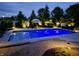 Beautiful, lit, backyard swimming pool at dusk surrounded by trees and landscaping at 3335 Guilford Ln, Plainfield, IN 46168