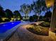 Backyard view of the inviting pool and patio, surrounded by lush landscaping and ambient outdoor lighting at 3335 Guilford Ln, Plainfield, IN 46168