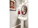 Charming powder room with pedestal sink, decorative mirror, sconce lighting, and a decorative painting at 3335 Guilford Ln, Plainfield, IN 46168