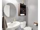 Neutral bathroom with white pedestal sink, round mirror, toilet, and storage cabinet at 442 Mozart Dr, Greenfield, IN 46140