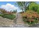Stone staircase with lush landscaping and vibrant flowers leads to the upper level of the backyard at 4614 Thornleigh Dr, Indianapolis, IN 46226