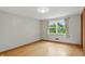 An empty bedroom with hardwood floors, light gray walls, and a window with beige curtains at 4614 Thornleigh Dr, Indianapolis, IN 46226