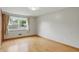 An empty bedroom with hardwood floors, light gray walls, and a window with beige curtains at 4614 Thornleigh Dr, Indianapolis, IN 46226