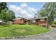 Well-maintained red brick home with a lush green lawn and colorful flowerbeds leading to the front door at 4614 Thornleigh Dr, Indianapolis, IN 46226
