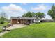 Back exterior view of home featuring a brick facade, sunroom, patio, and expansive grassy area at 4614 Thornleigh Dr, Indianapolis, IN 46226