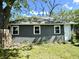 View of a grey cinder block detached garage with three windows and a white door in a green yard at 4814 E New York St, Indianapolis, IN 46201