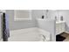 Bright bathroom showcasing a soaking tub with decorative tile and a separate sink and vanity at 5420 Orwell Ct, Indianapolis, IN 46239