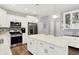 Spacious kitchen featuring stainless steel appliances, white cabinets, an island, and access to dining area and staircase at 5420 Orwell Ct, Indianapolis, IN 46239