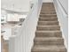 Carpeted staircase with white banister, seamlessly connecting to the bright and modern kitchen at 5420 Orwell Ct, Indianapolis, IN 46239