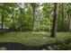 View of backyard featuring lush grass, mature trees, and black iron fencing at 7775 N Meridian St, Indianapolis, IN 46260