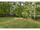 View of backyard featuring lush grass, mature trees, and black iron fencing at 7775 N Meridian St, Indianapolis, IN 46260