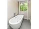 Elegant bathroom with a freestanding soaking tub, gray tile floors and a large window at 7775 N Meridian St, Indianapolis, IN 46260