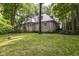 Beautiful backyard view of the stone home, surrounded by a lush lawn and trees at 7775 N Meridian St, Indianapolis, IN 46260