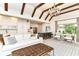 Open living room with hardwood floors, fireplace, exposed beams, and view to kitchen with island and seating at 7775 N Meridian St, Indianapolis, IN 46260