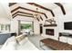 Bright living room features exposed beam vaulted ceilings, a fireplace, and a large window with a view to a green backyard at 7775 N Meridian St, Indianapolis, IN 46260