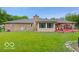 Spacious backyard with a well-maintained lawn, brick house, and a sunroom at 813 Boulder Rd, Indianapolis, IN 46217