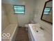 Bathroom featuring a tub with tile surround, a single sink vanity, and natural light at 907 Monroe St, Indianapolis, IN 46229