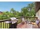 Outdoor wooden deck with a barbecue grill, table with chairs, and green trees surrounding the property at 976 Santa Maria Dr, Greenwood, IN 46143