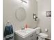 Charming half bath featuring a stylish vanity, circular mirror, wall decor and modern fixtures at 9771 Blue Violet Dr, Noblesville, IN 46060