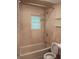 Neutral toned bathroom features a tub and shower, window, and toilet in a well-lit space at 1008 E 61St St, Indianapolis, IN 46220