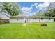 Green backyard showcasing the home's exterior with a fire pit and well-maintained lawn at 10097 N Balfer E Dr, Fortville, IN 46040