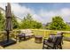 Outdoor deck featuring modern seating, a fire pit, and an umbrella overlooking the backyard and lake at 11552 Buckskin Dr, Zionsville, IN 46077