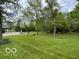 Expansive backyard with mature trees, lush green lawn, and a garage in the distance, offering ample space and privacy at 11898 N 200 W, Fountaintown, IN 46130