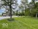 Spacious backyard with lush green lawn, mature trees, and gravel driveway leading to a garage at 11898 N 200 W, Fountaintown, IN 46130