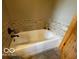 Bathtub with tiled surround, complemented by wooden door detail at 11898 N 200 W, Fountaintown, IN 46130