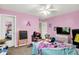 Bright pink bedroom with ceiling fan, tv, and personal items at 15264 Ten Point Dr, Noblesville, IN 46060
