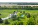 An aerial shot showcases a luxurious home with pool and playground, nestled among lush green landscapes and tree lined border at 1820 N 1100 E, Sheridan, IN 46069