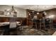 Home bar featuring wood paneling, slate floor, marble countertop, storage shelves, bar stools, and nearby eating area at 1820 N 1100 E, Sheridan, IN 46069