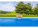 Pool with waterfall feature surrounded by a lush green yard, and backyard trampoline at 1820 N 1100 E, Sheridan, IN 46069
