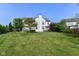 A large backyard with lush lawn, mature trees, and a glimpse of the rear of the house at 18967 Mill Grove Dr, Noblesville, IN 46062