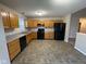 Kitchen boasts black appliances, oak cabinets, and neutral countertops, with vinyl flooring and a half wall to dining at 356 Seabreeze Cir, Avon, IN 46123
